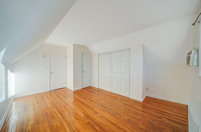 additional living space with light hardwood / wood-style floors and vaulted ceiling