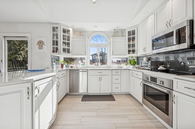 kitchen featuring stainless steel appliances, tasteful backsplash, sink, and white cabinets