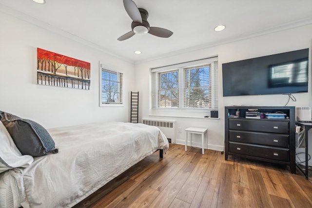 bedroom with hardwood / wood-style flooring, crown molding, radiator heating unit, and multiple windows