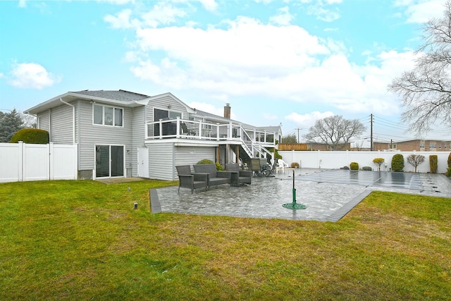 back of property featuring a lawn, a wooden deck, and a patio