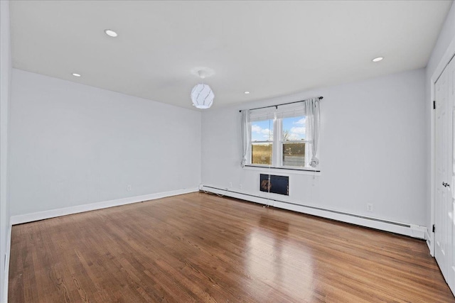 empty room with baseboard heating and hardwood / wood-style flooring