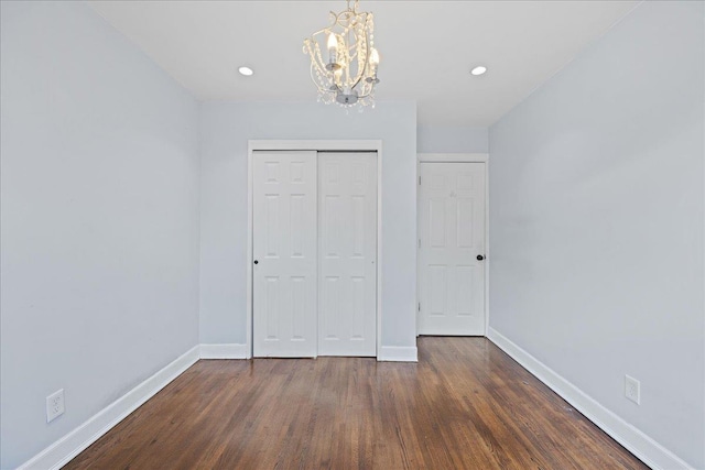 unfurnished bedroom featuring a chandelier, a closet, and dark wood-type flooring