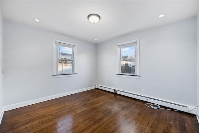 unfurnished room featuring baseboard heating and dark hardwood / wood-style floors