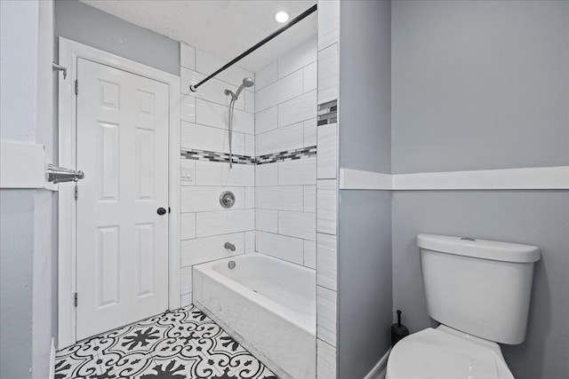 bathroom with tile patterned flooring, toilet, and tiled shower / bath