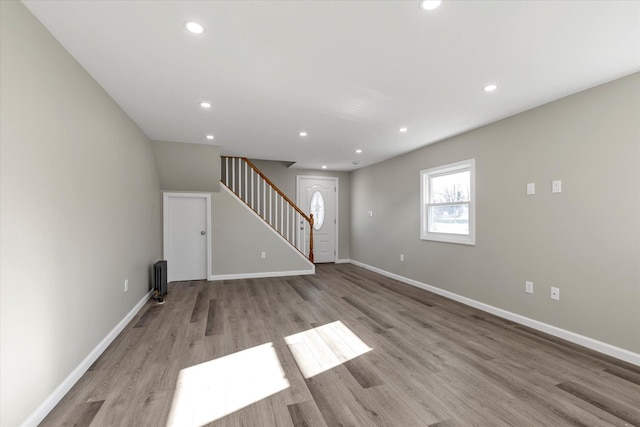 unfurnished living room with radiator heating unit and light wood-type flooring