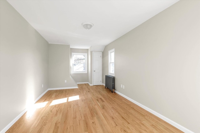 unfurnished room featuring radiator heating unit and light hardwood / wood-style flooring