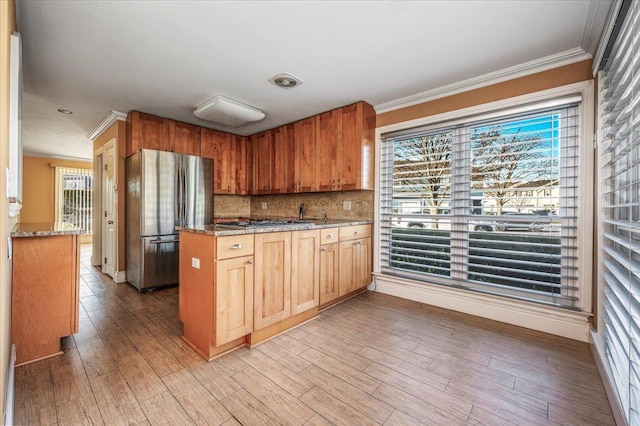 kitchen featuring decorative backsplash, light hardwood / wood-style flooring, stainless steel appliances, and ornamental molding