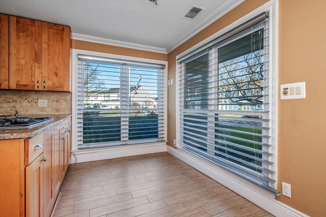 kitchen featuring light hardwood / wood-style floors, stainless steel gas cooktop, tasteful backsplash, and ornamental molding