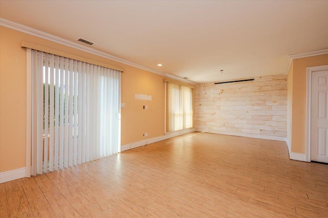 unfurnished room featuring wooden walls, light hardwood / wood-style flooring, a healthy amount of sunlight, and ornamental molding