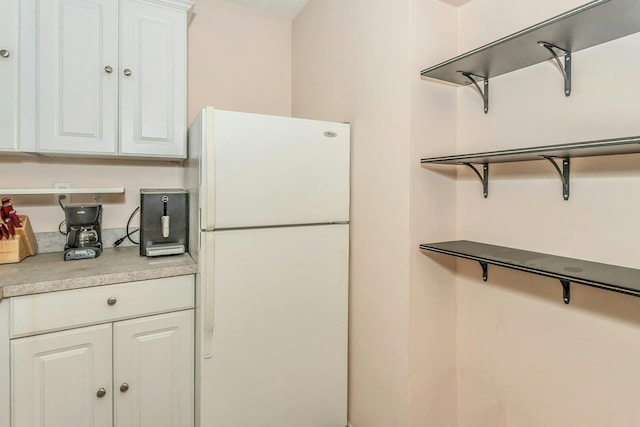 kitchen featuring white fridge and white cabinetry