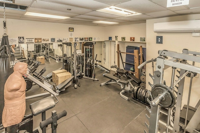 workout area with a paneled ceiling and an AC wall unit