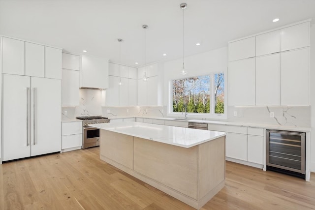 kitchen with pendant lighting, high end appliances, light hardwood / wood-style floors, a kitchen island, and beverage cooler