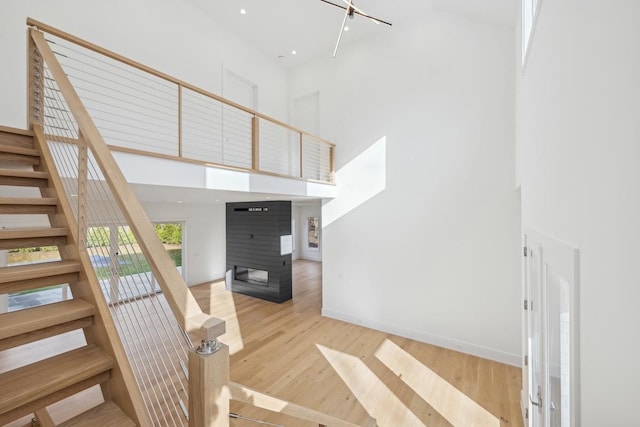 staircase with a towering ceiling and wood-type flooring