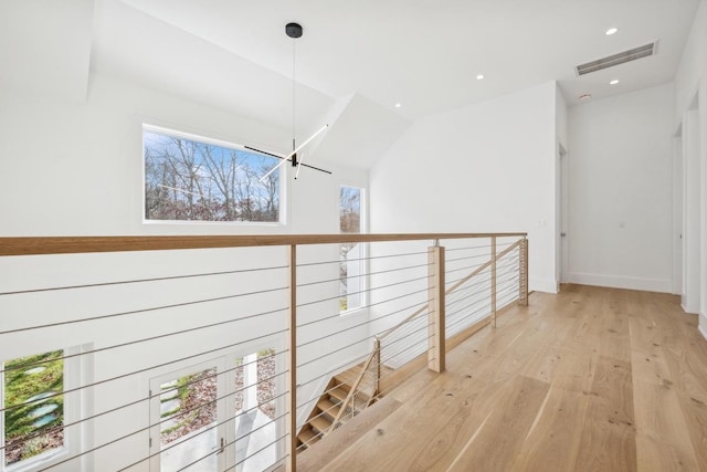 corridor with light hardwood / wood-style floors and vaulted ceiling