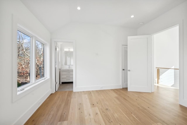 unfurnished bedroom featuring vaulted ceiling, light hardwood / wood-style floors, and ensuite bath