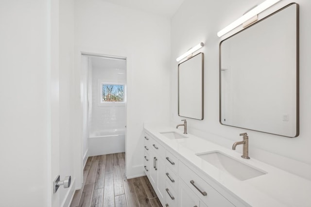 bathroom featuring washtub / shower combination, vanity, and hardwood / wood-style flooring