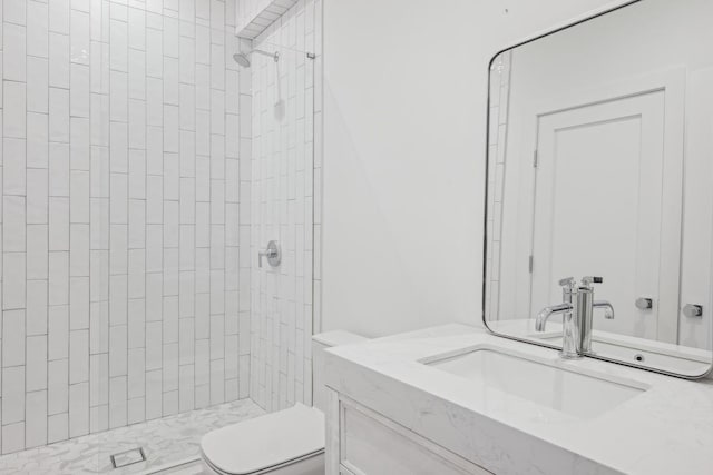 bathroom with vanity, toilet, and tiled shower