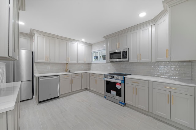 kitchen featuring appliances with stainless steel finishes, gray cabinets, tasteful backsplash, and sink