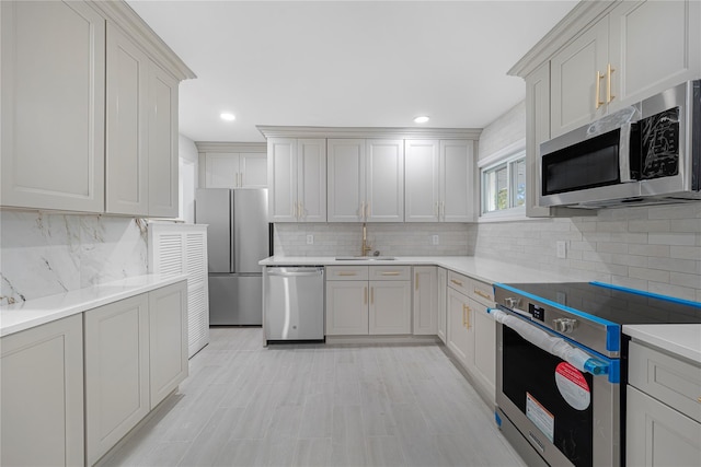 kitchen with tasteful backsplash, sink, and appliances with stainless steel finishes