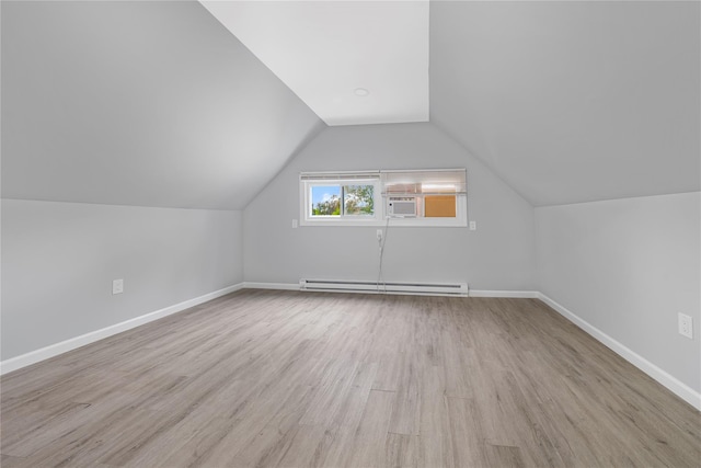 additional living space featuring cooling unit, lofted ceiling, light hardwood / wood-style flooring, and a baseboard heating unit