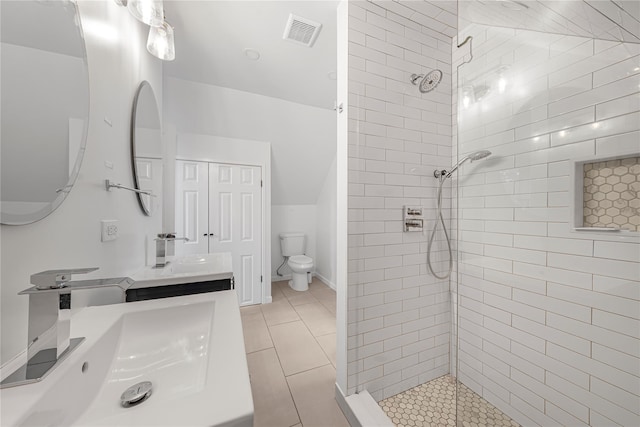 bathroom featuring tile patterned flooring, a tile shower, vanity, and toilet