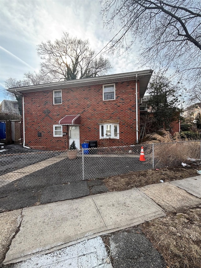 back of house featuring fence and brick siding