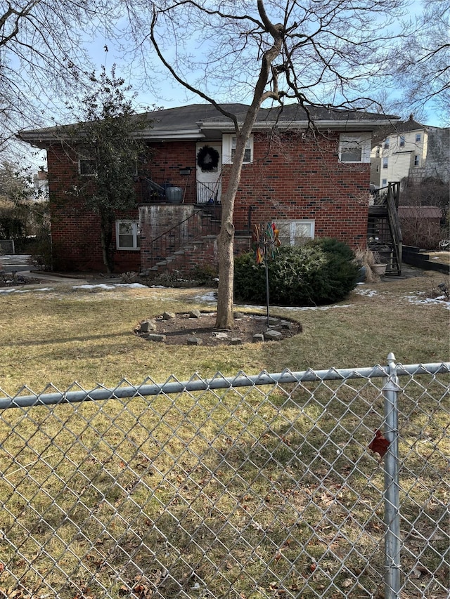 view of front of property with stairway, a front yard, fence, and brick siding