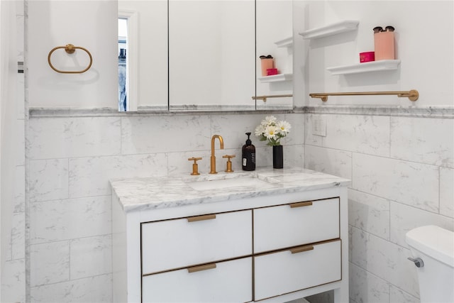 bathroom with vanity, tile walls, and toilet