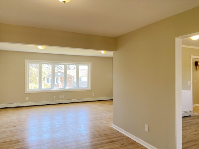 empty room with ornamental molding, a baseboard radiator, and light hardwood / wood-style flooring