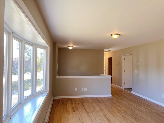 unfurnished room with light hardwood / wood-style flooring and baseboard heating