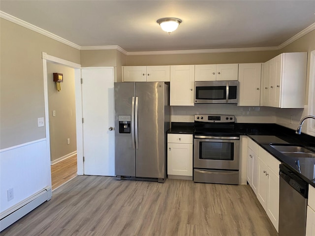 kitchen featuring white cabinets, light wood-type flooring, baseboard heating, and appliances with stainless steel finishes