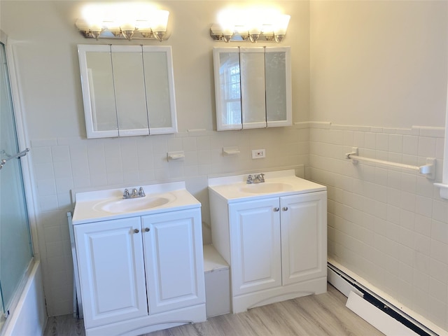 bathroom with hardwood / wood-style flooring, vanity, baseboard heating, and tile walls