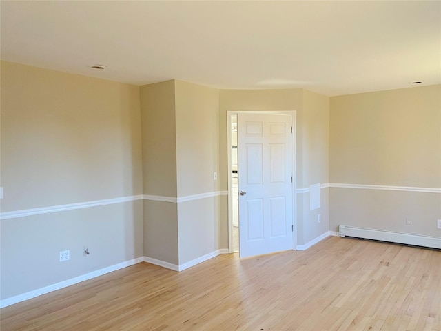 unfurnished room featuring baseboard heating and light hardwood / wood-style flooring