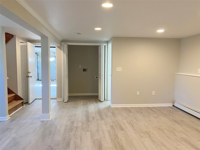 unfurnished room with a baseboard heating unit, light hardwood / wood-style floors, and crown molding