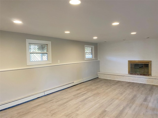 basement featuring a fireplace, light hardwood / wood-style floors, and baseboard heating