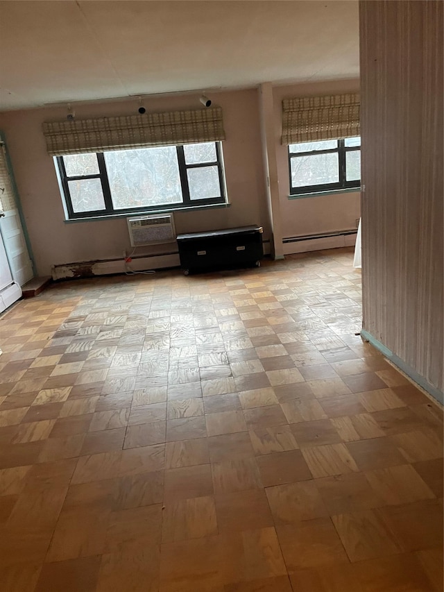 unfurnished room featuring a wall mounted air conditioner and a baseboard radiator