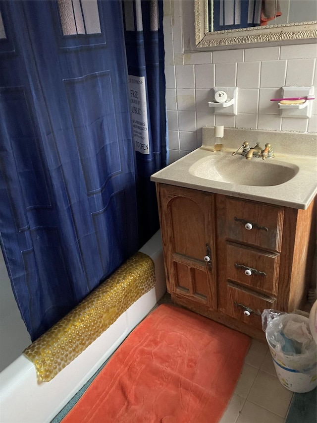 bathroom with tile patterned flooring, backsplash, shower / bath combo with shower curtain, and sink