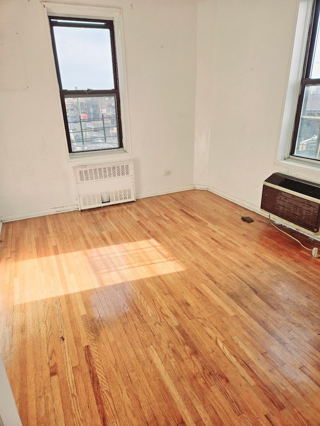 empty room with radiator, a wealth of natural light, and light wood-type flooring