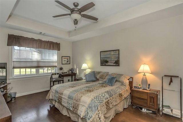 bedroom with a raised ceiling, ceiling fan, and dark wood-type flooring