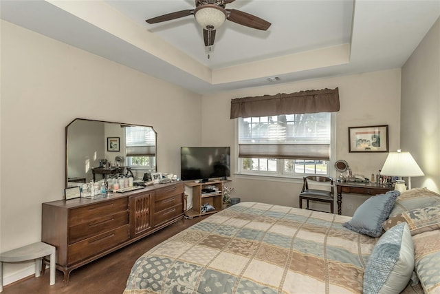 bedroom featuring a tray ceiling, ceiling fan, and dark wood-type flooring