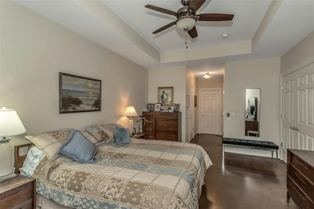 bedroom with dark hardwood / wood-style flooring, a raised ceiling, and ceiling fan