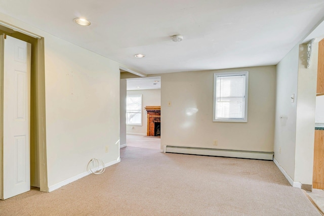 carpeted empty room with a brick fireplace and baseboard heating