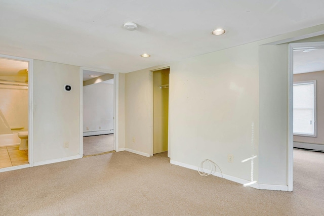 unfurnished room featuring light colored carpet and a baseboard radiator