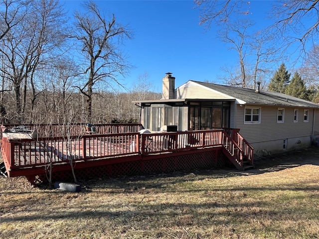 back of property featuring a lawn, a sunroom, and a deck