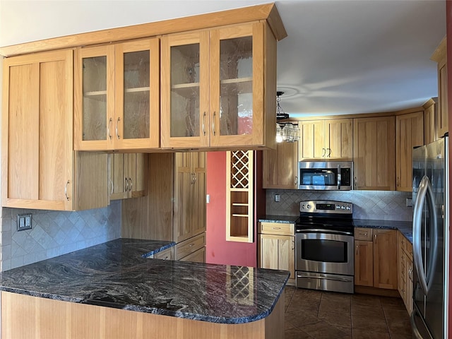 kitchen featuring kitchen peninsula, tasteful backsplash, stainless steel appliances, dark stone countertops, and hanging light fixtures