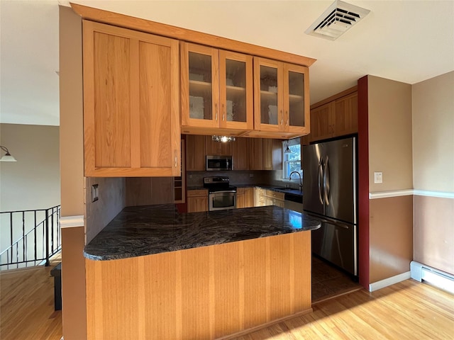 kitchen featuring kitchen peninsula, stainless steel appliances, hardwood / wood-style flooring, and sink