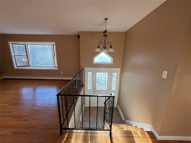 foyer entrance featuring hardwood / wood-style floors, a baseboard radiator, a wealth of natural light, and an inviting chandelier