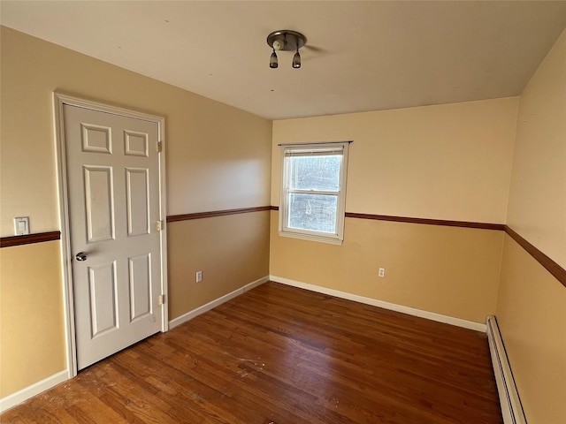 unfurnished room featuring dark hardwood / wood-style flooring and a baseboard heating unit