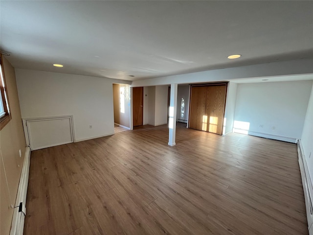 empty room with light wood-type flooring and a baseboard heating unit