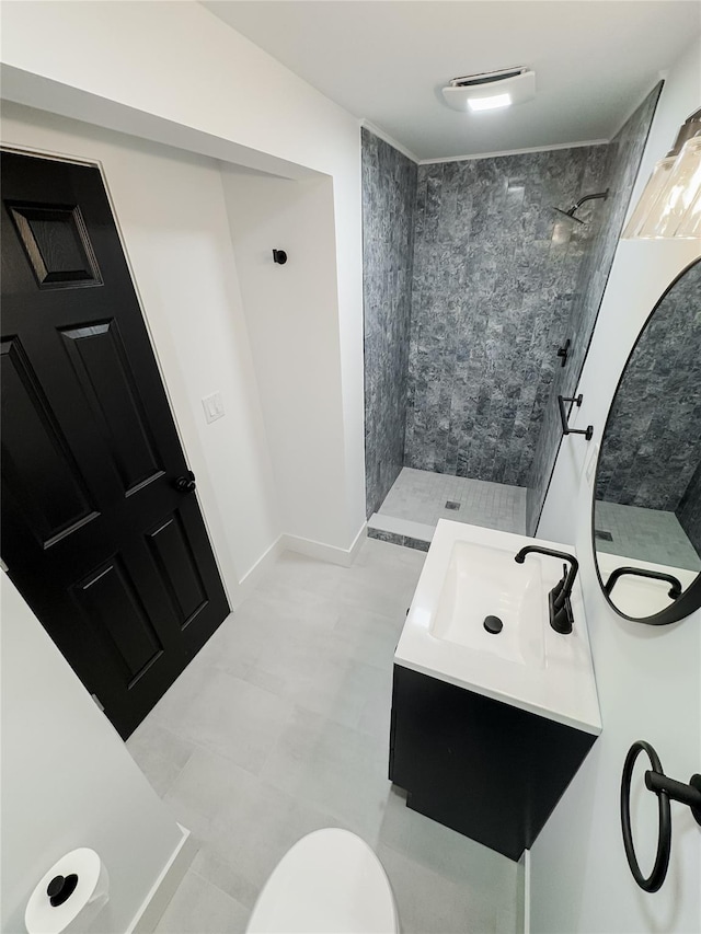 bathroom with toilet, vanity, and tiled shower